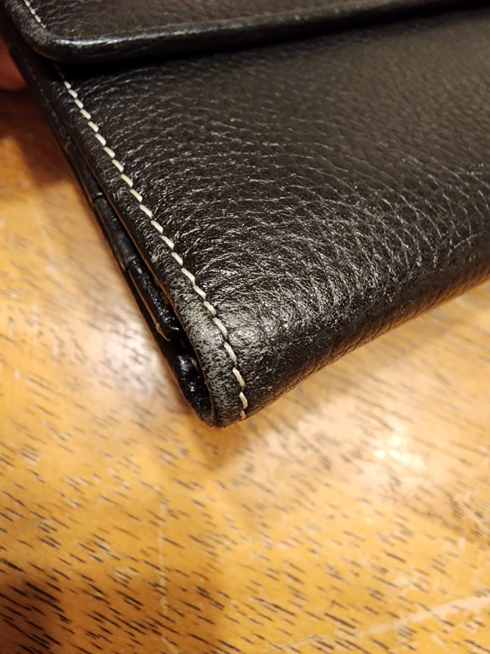 black Christian Dior pebbled leather trifold long wallet featuring gold-tone 